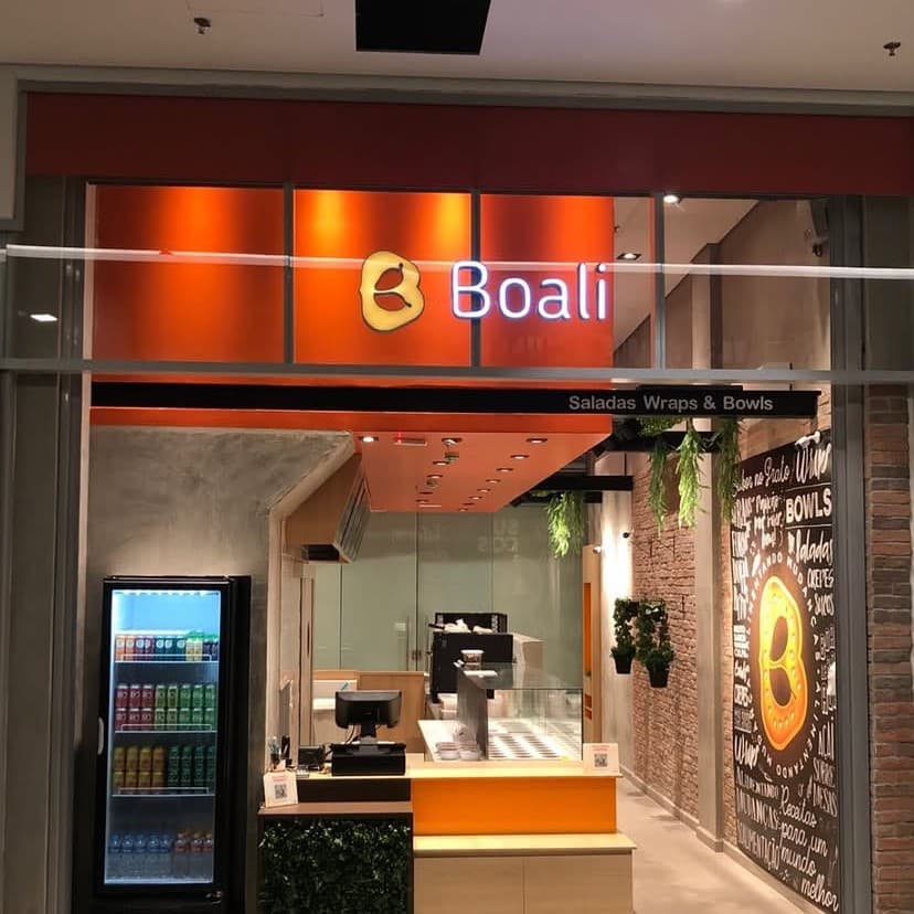 Fachada do restaurante Boali, com letreiro laranja, balcão de atendimento e painel decorativo em giz.